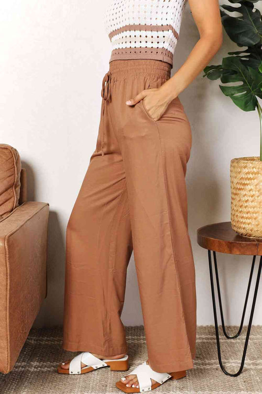 Crafted with a drawstring-smocked waist, these Women's wide-leg pants offer comfort and a flattering silhouette. Their extended length exudes elegance, making them suitable for casual or formal settings. Effortlessly stylish and versatile, these pants are an excellent choice for creating trendy yet comfortable ensembles.